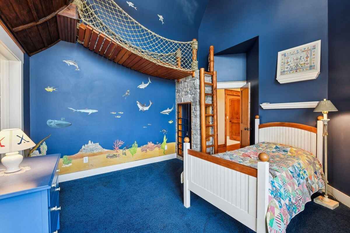 A themed bedroom with underwater wall art, a net bridge, and a wooden loft area.