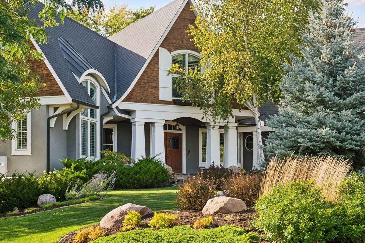 A close-up view of the home entrance showcasing its pillars, arched rooflines, and landscaping.