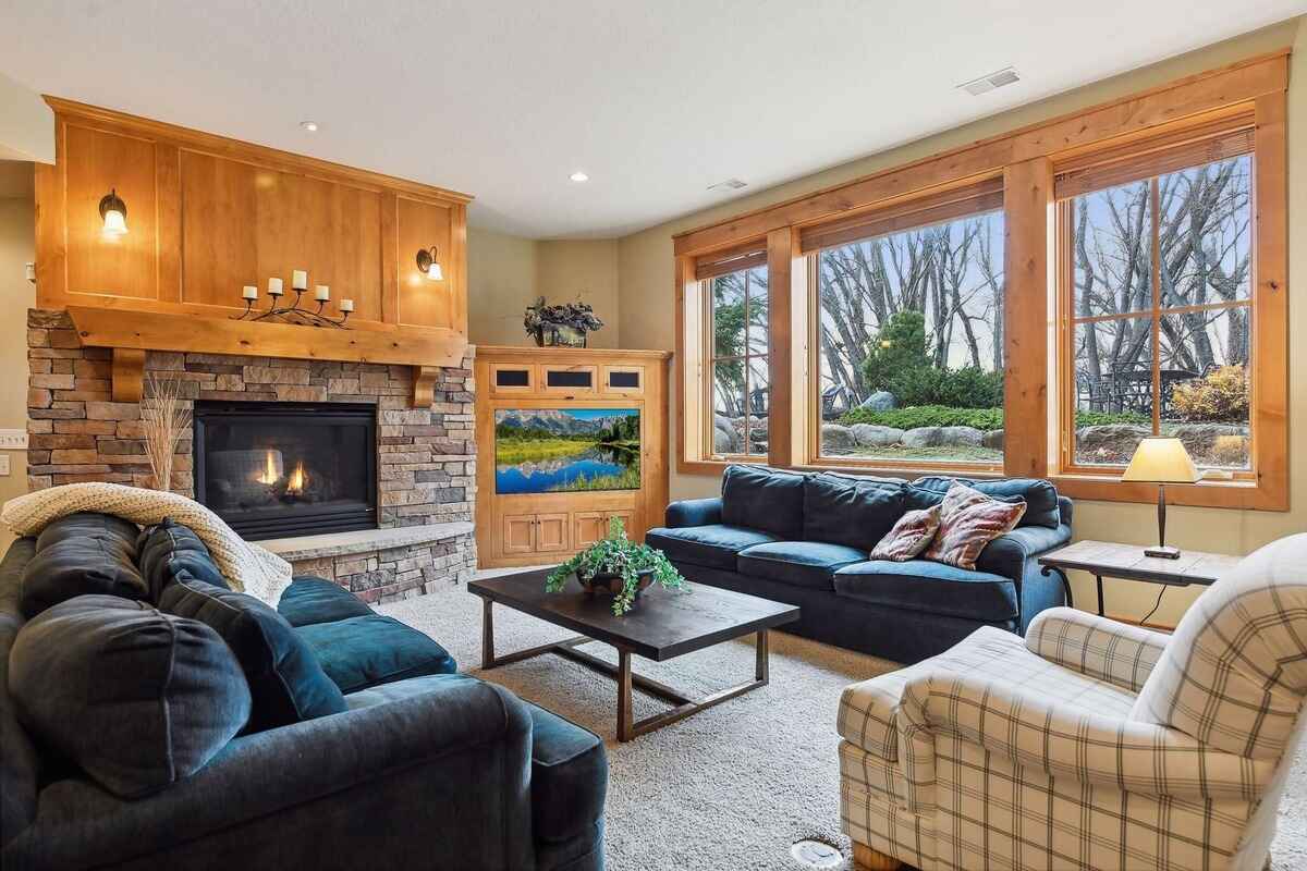 Family room includes a stone fireplace, built-in wood cabinetry, and large windows overlooking the yard.