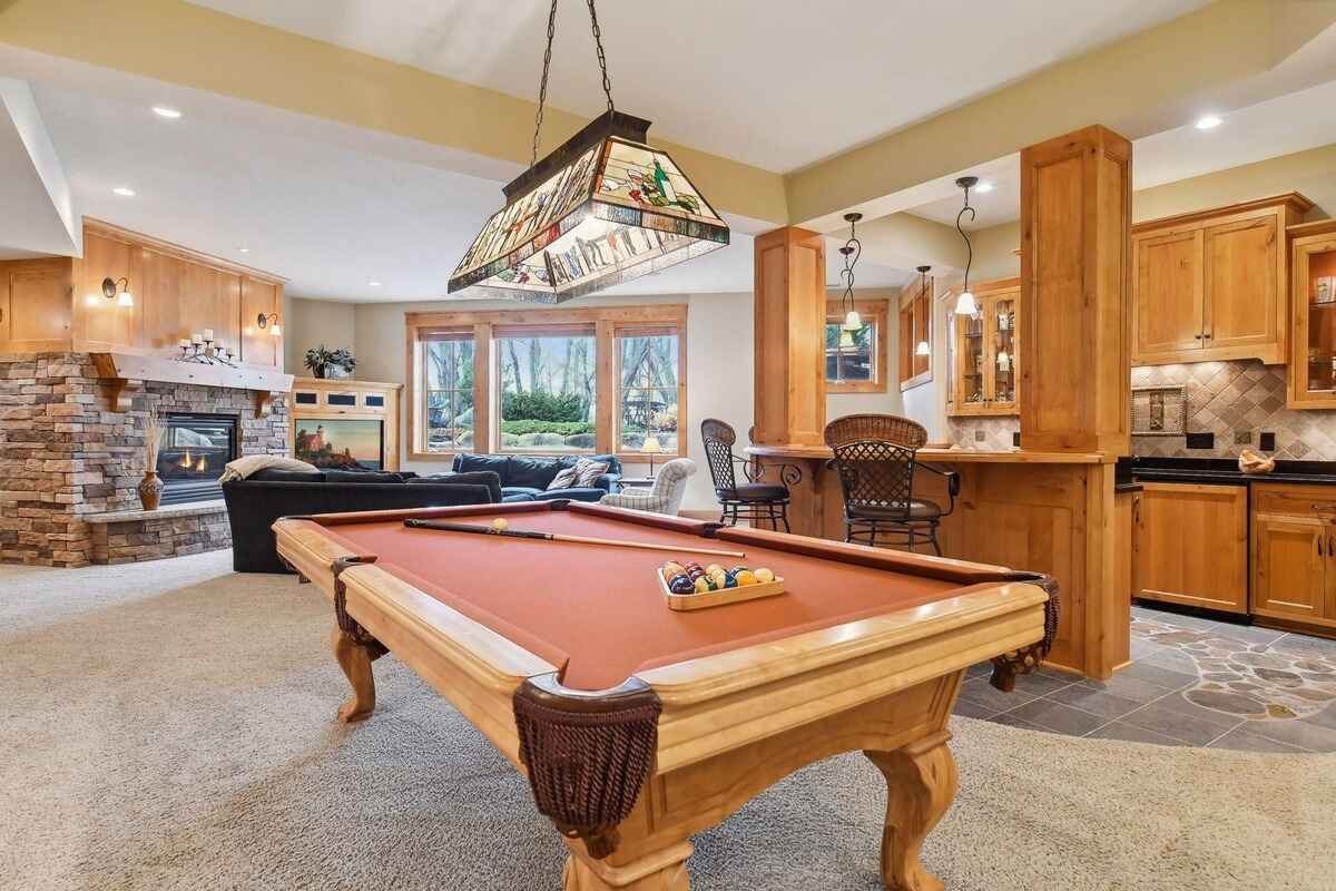 A game room with a pool table, fireplace, wet bar, and comfortable seating area.