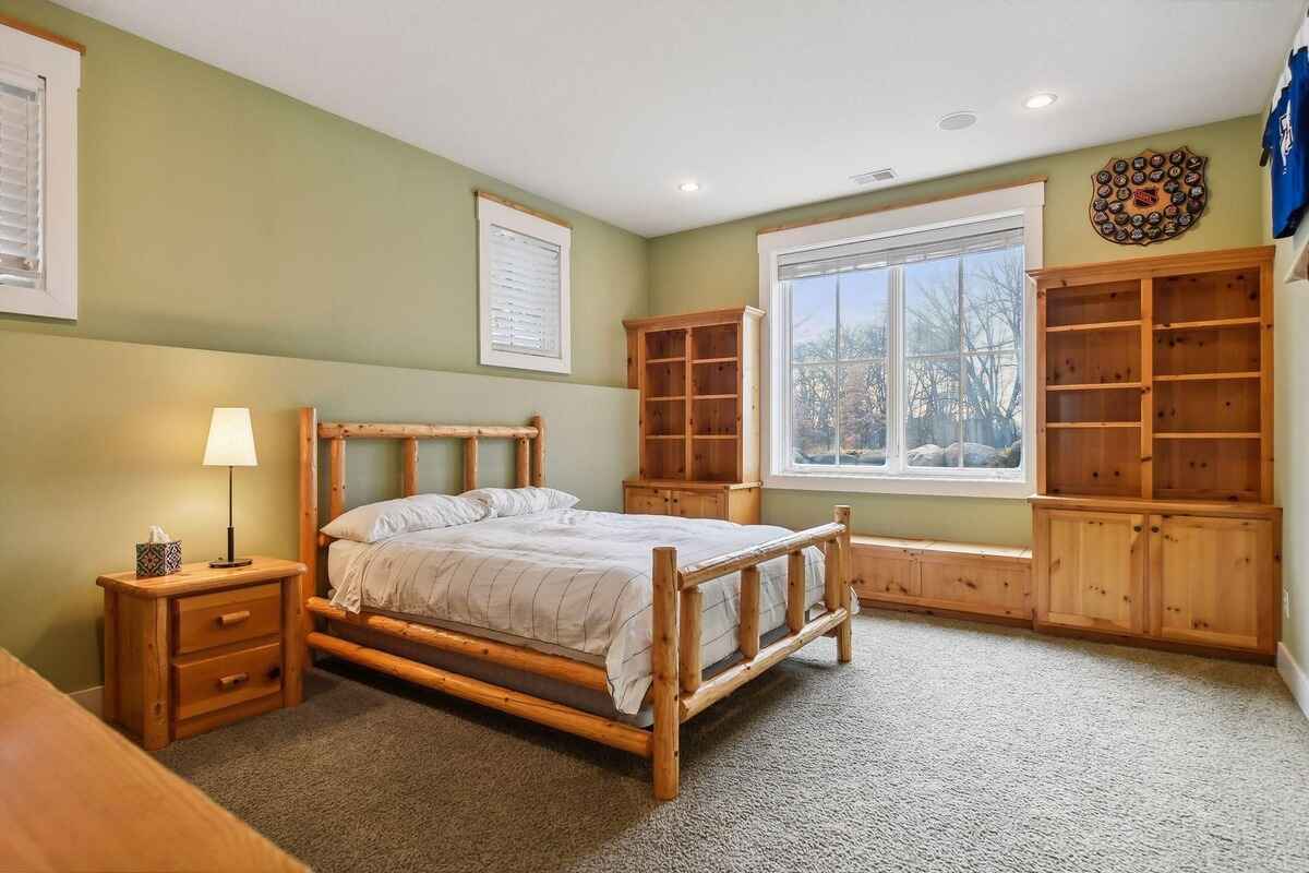 Log bed frame and wooden shelving complement the light green walls of the bedroom.