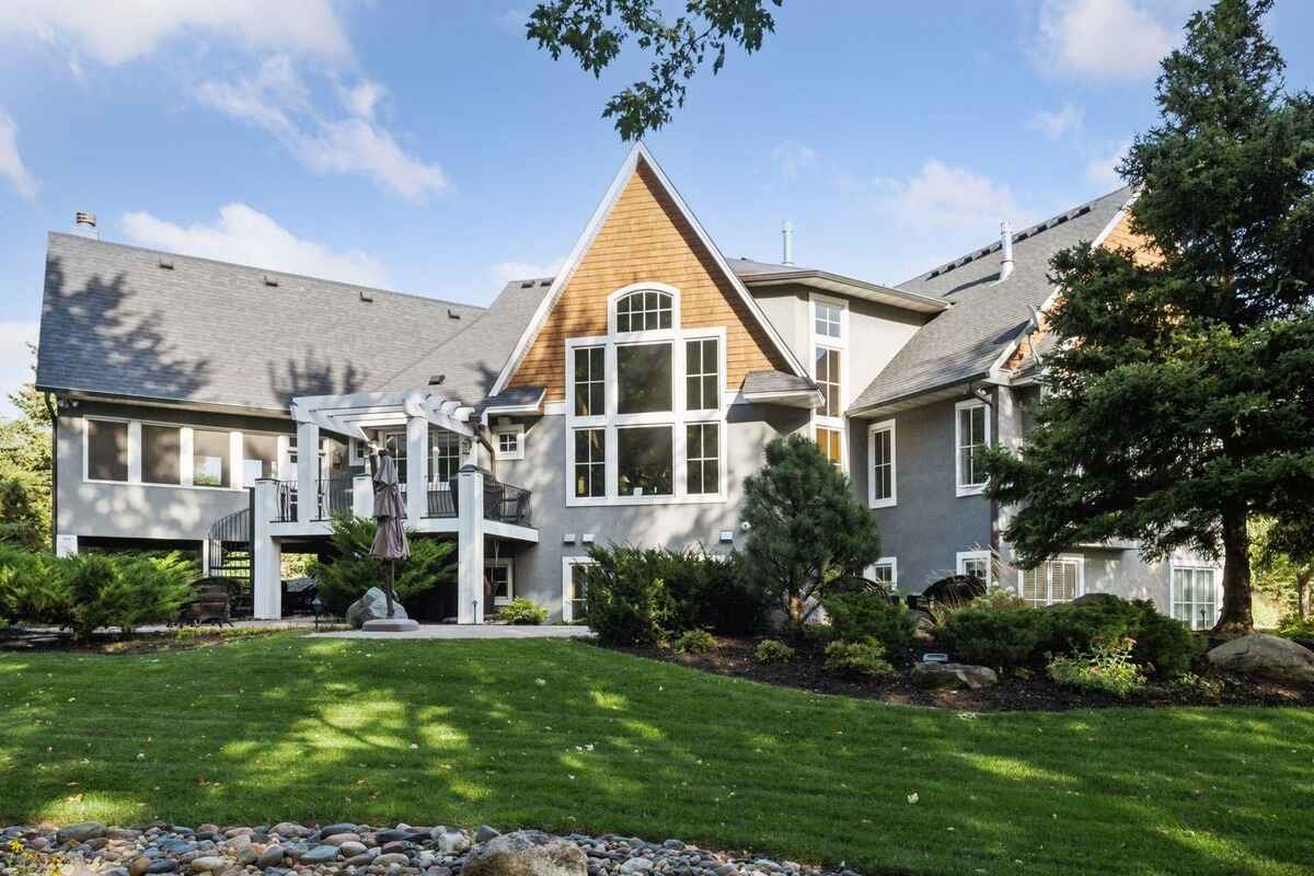 Large gray house with a wood-shingled section, a deck, and landscaping.