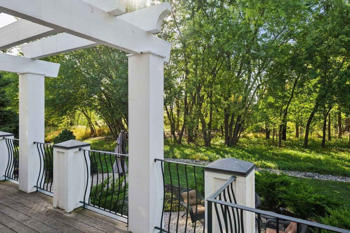 Deck with white pergola overlooking a wooded area.