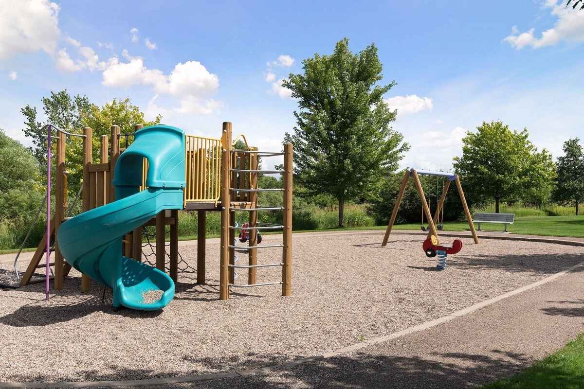 Playground with a climbing structure, slide, swings, and spring rider.