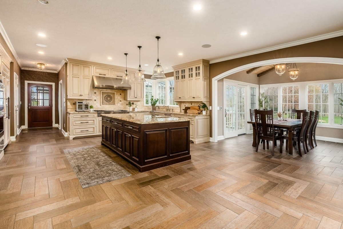 Spacious kitchen with an island, wood flooring, and custom cabinetry extending into the dining area.