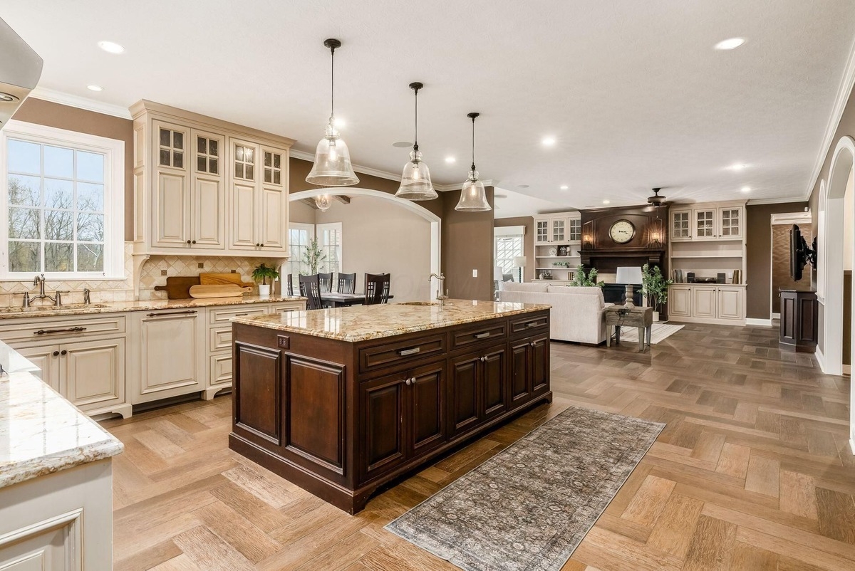 Open-concept kitchen and living area with an island and adjacent seating areas under bright lighting.