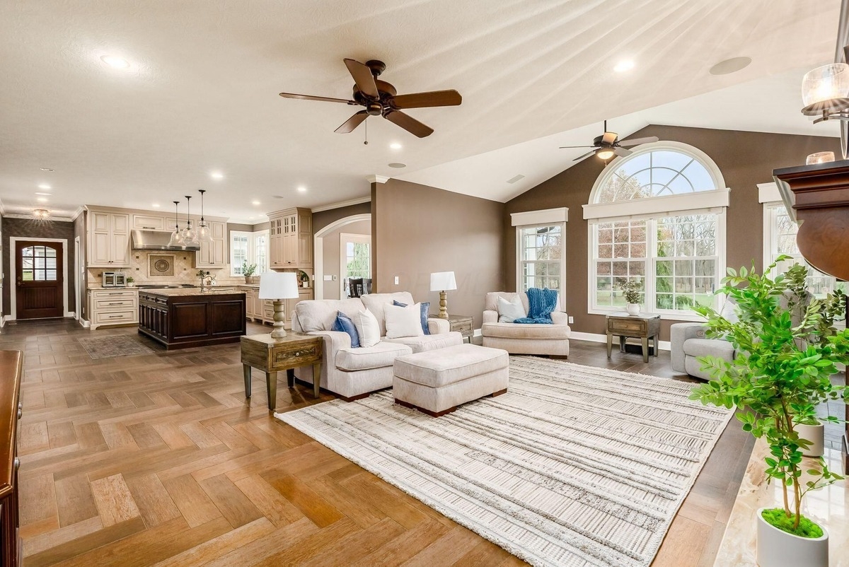 Open living room with vaulted ceilings, large windows, and hardwood floors.