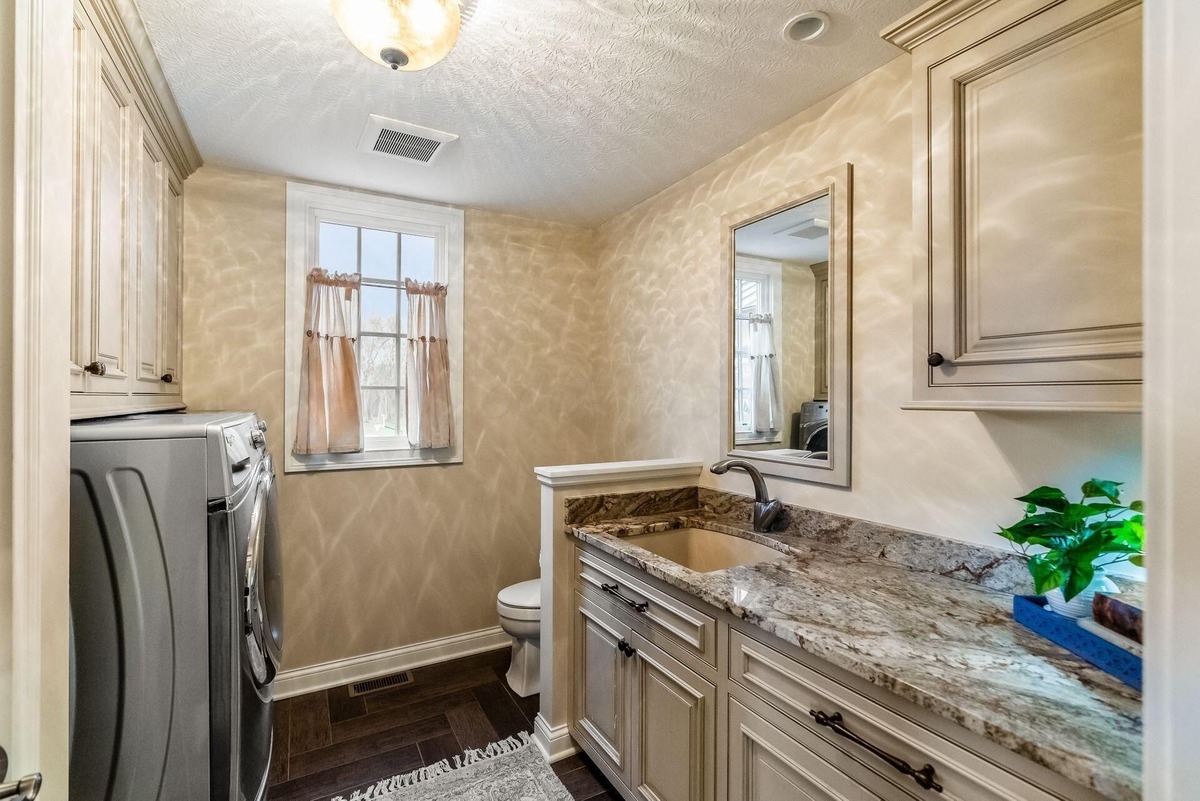 Laundry room with granite countertops, built-in cabinets, and a washer-dryer set.