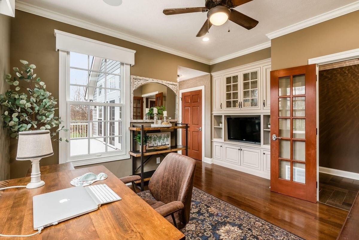 Home office with built-in shelving, a wooden desk, and a view of the yard through a large