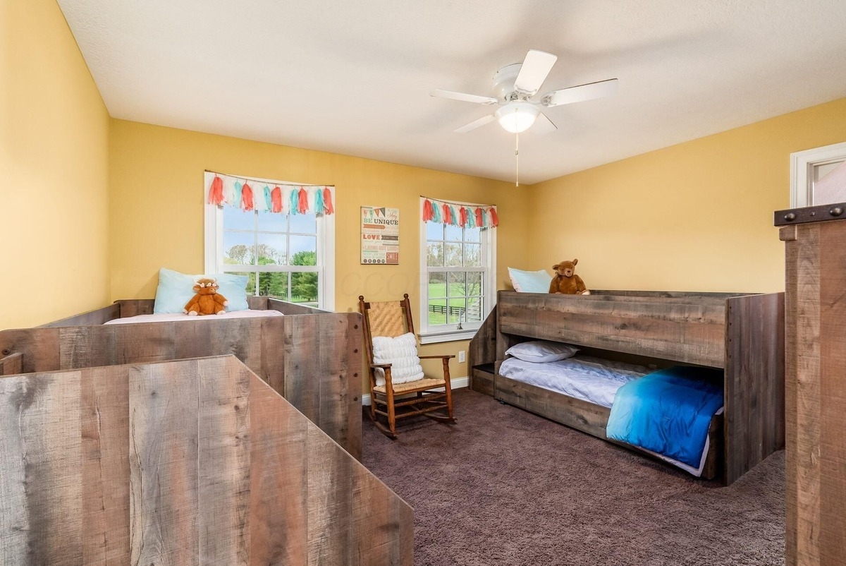 Children's bedroom with bunk beds, bright yellow walls, and a rocking chair.