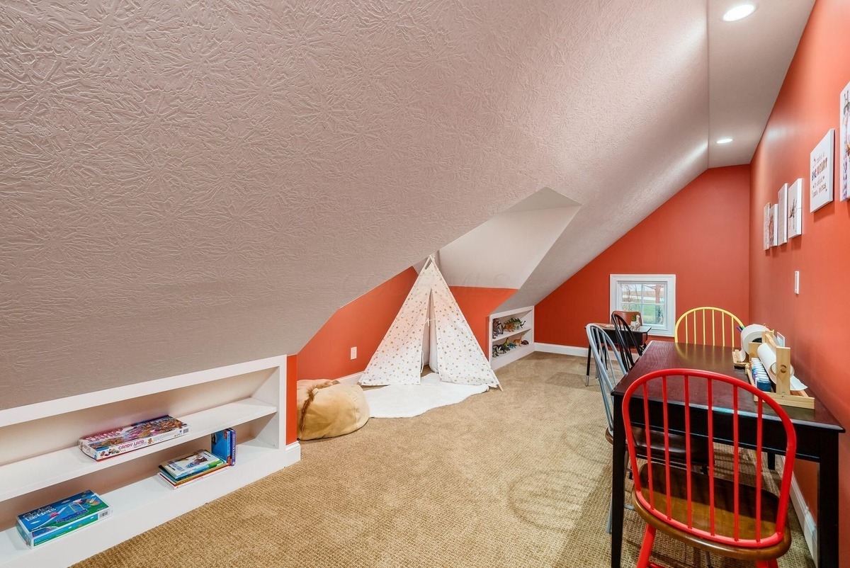 Playroom with sloped ceilings, colorful chairs, and built-in shelves for toys.