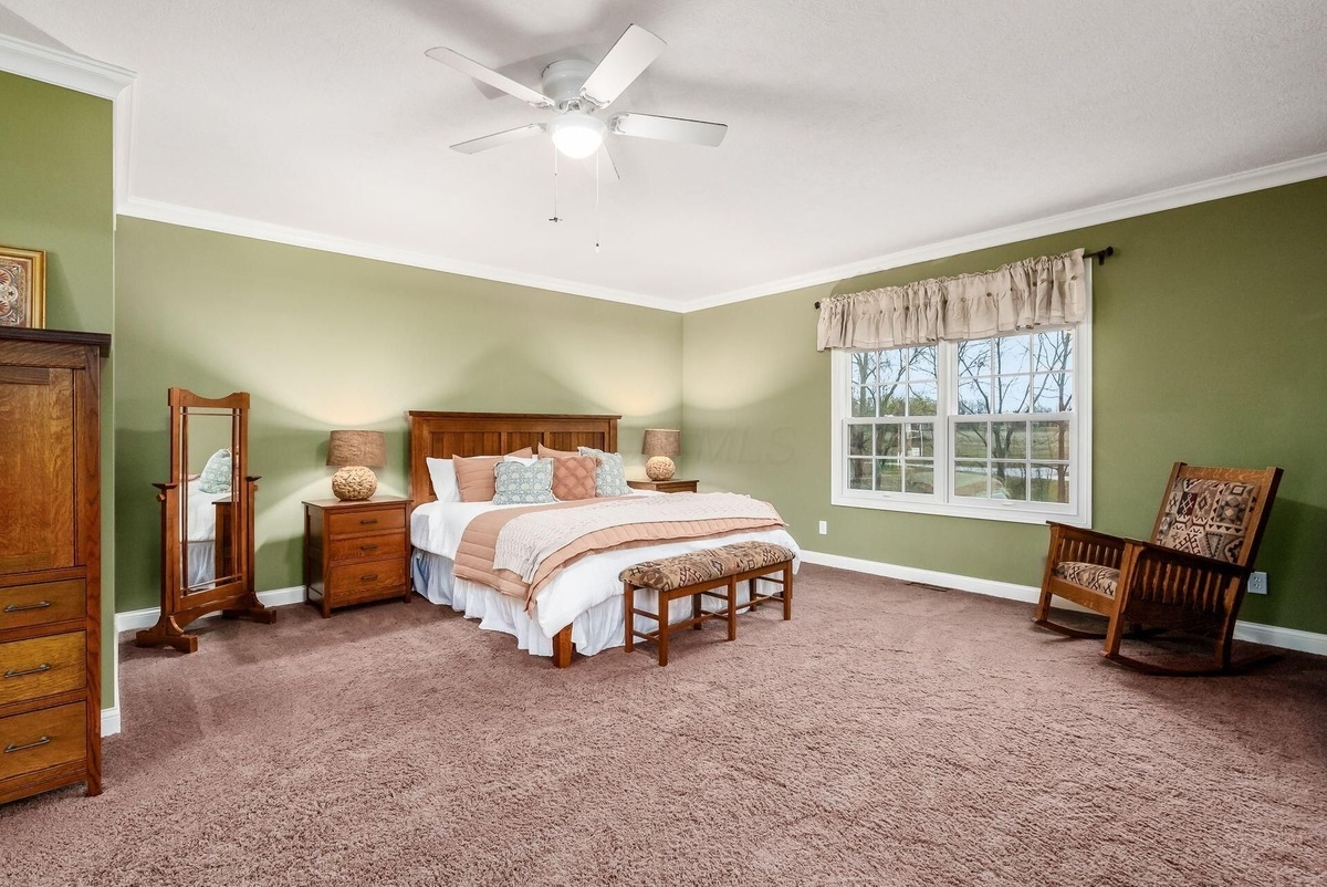 A spacious bedroom with green walls, a large bed, and traditional wooden furniture.