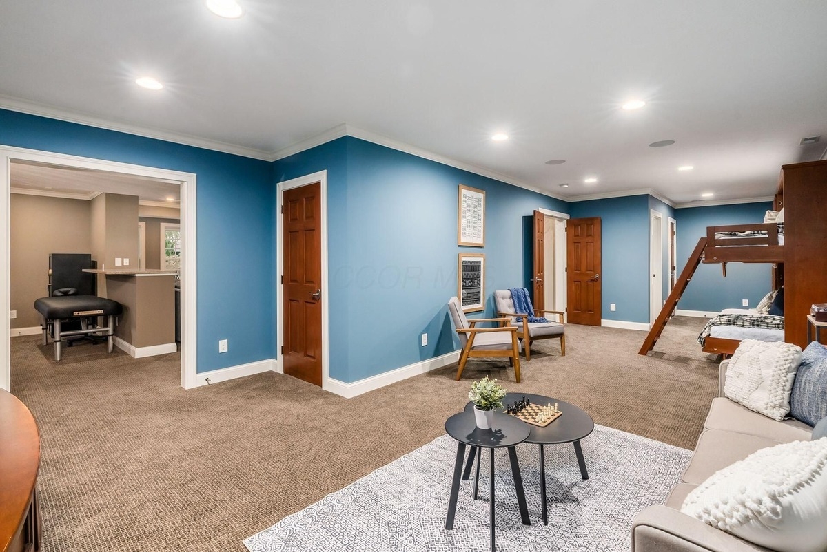 A blue-painted bonus room with seating and bunk beds, suitable for relaxation or guests.