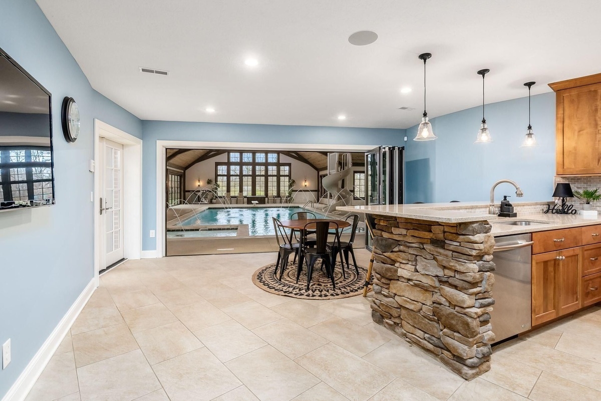 Indoor pool area with large windows, a slide, and adjacent lounge space.