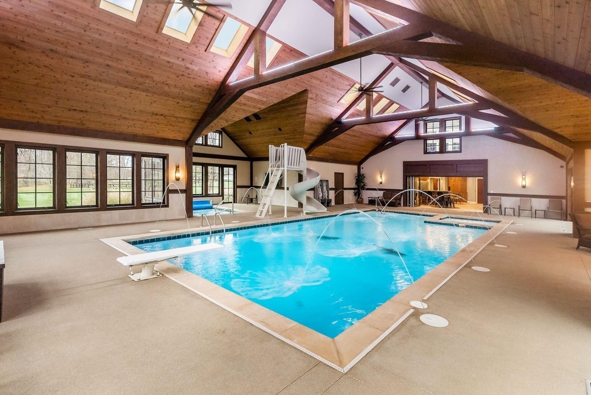 An indoor swimming pool with a slide and a vaulted wooden ceiling.