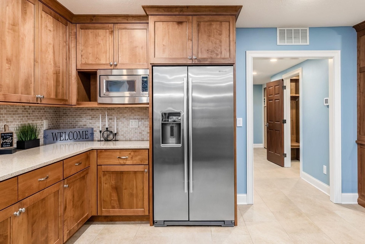 Kitchenette with wooden cabinets, stainless steel appliances, and tile backsplash.