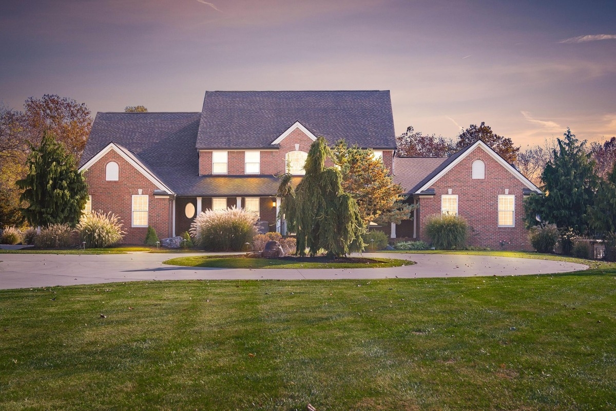 Brick exterior of a two-story house with a circular driveway in the front yard.