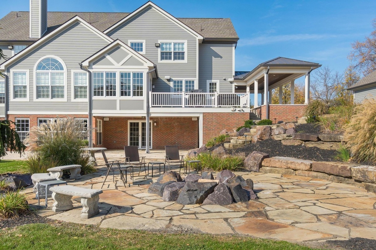 Back patio area with stone flooring, seating, and tiered landscaping.