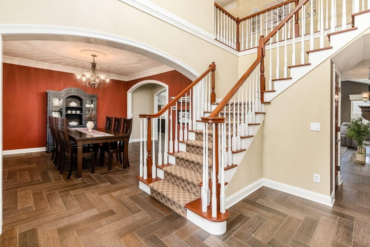 Grand staircase with carpeted steps leading to a formal dining area.