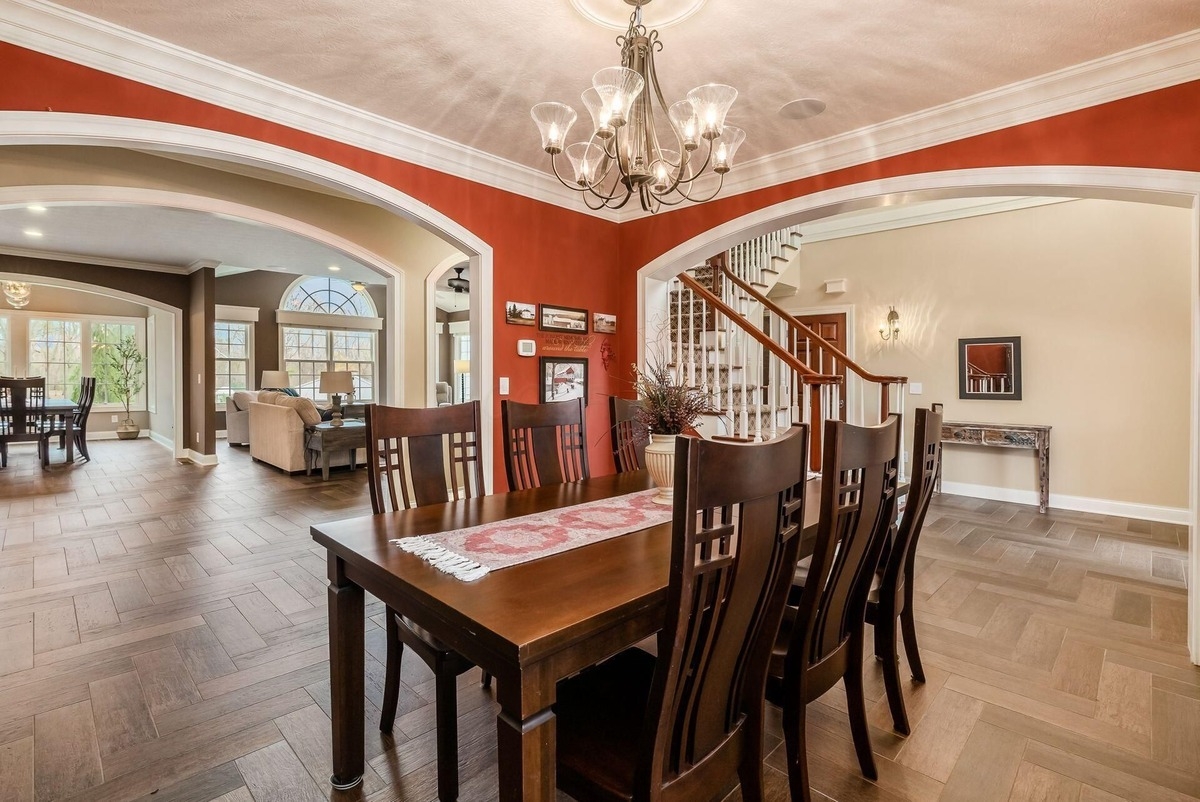 Formal dining room featuring arched doorways and wooden furniture with a view of the staircase.