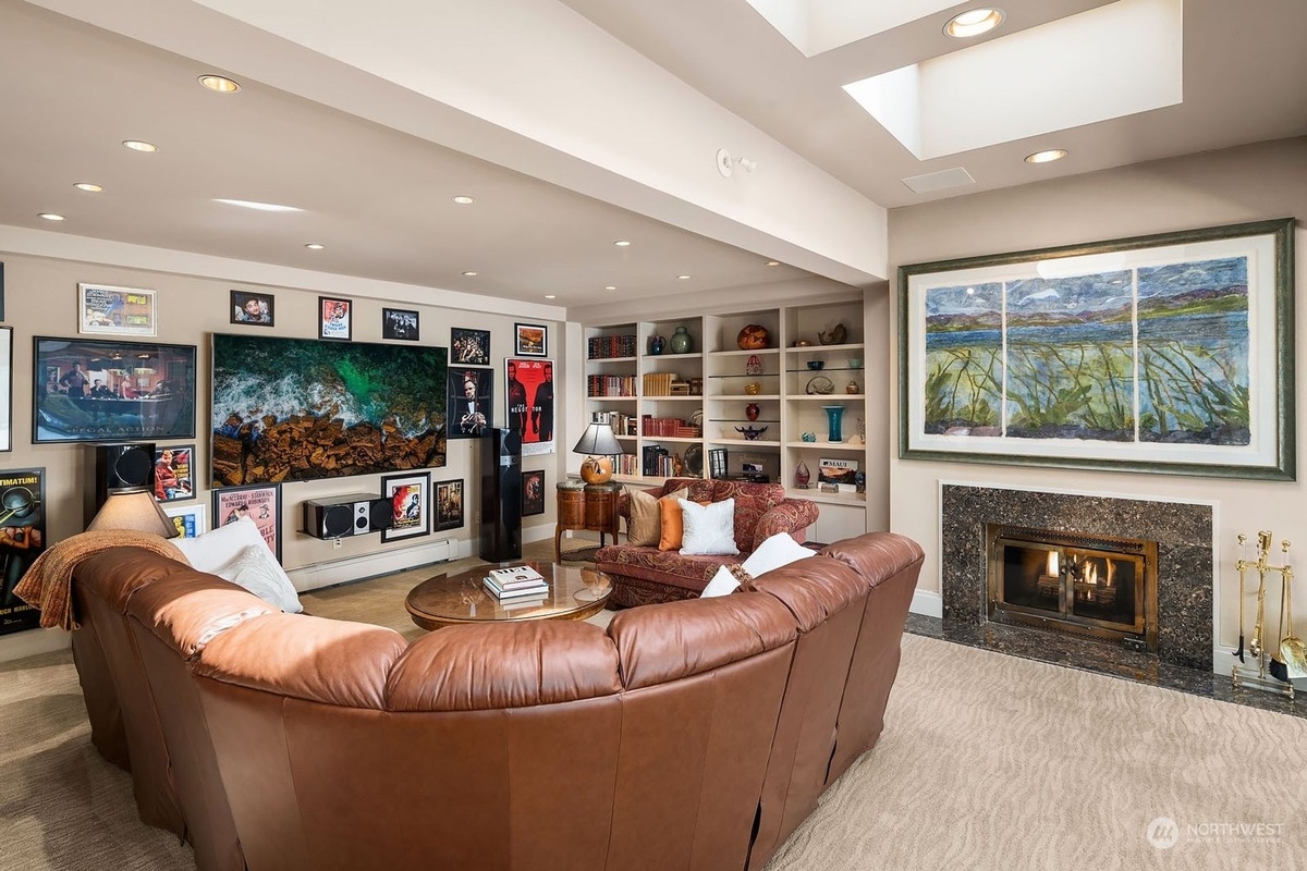 Large, curved leather sectional sofa faces a wall of movie posters and a large screen TV in a home theater.