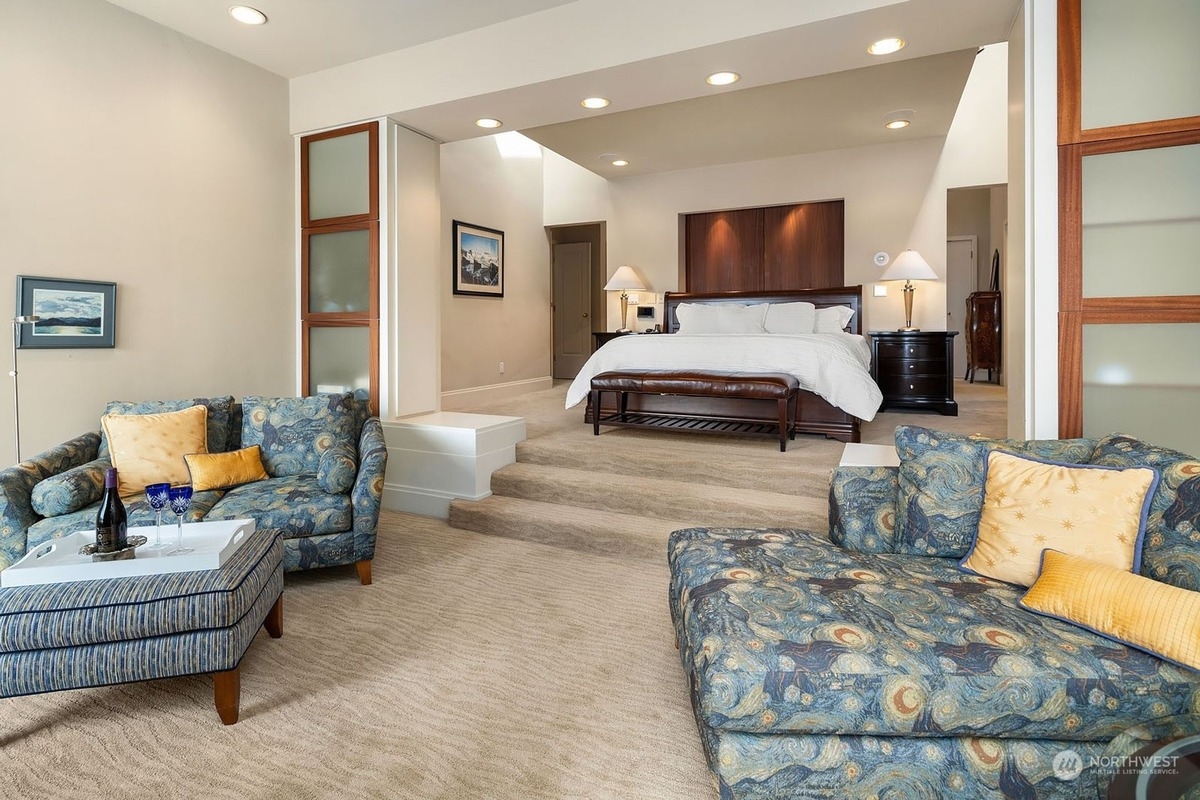 Master bedroom suite features a king-size bed, sitting area with unique patterned furniture, and a partially visible adjoining room.