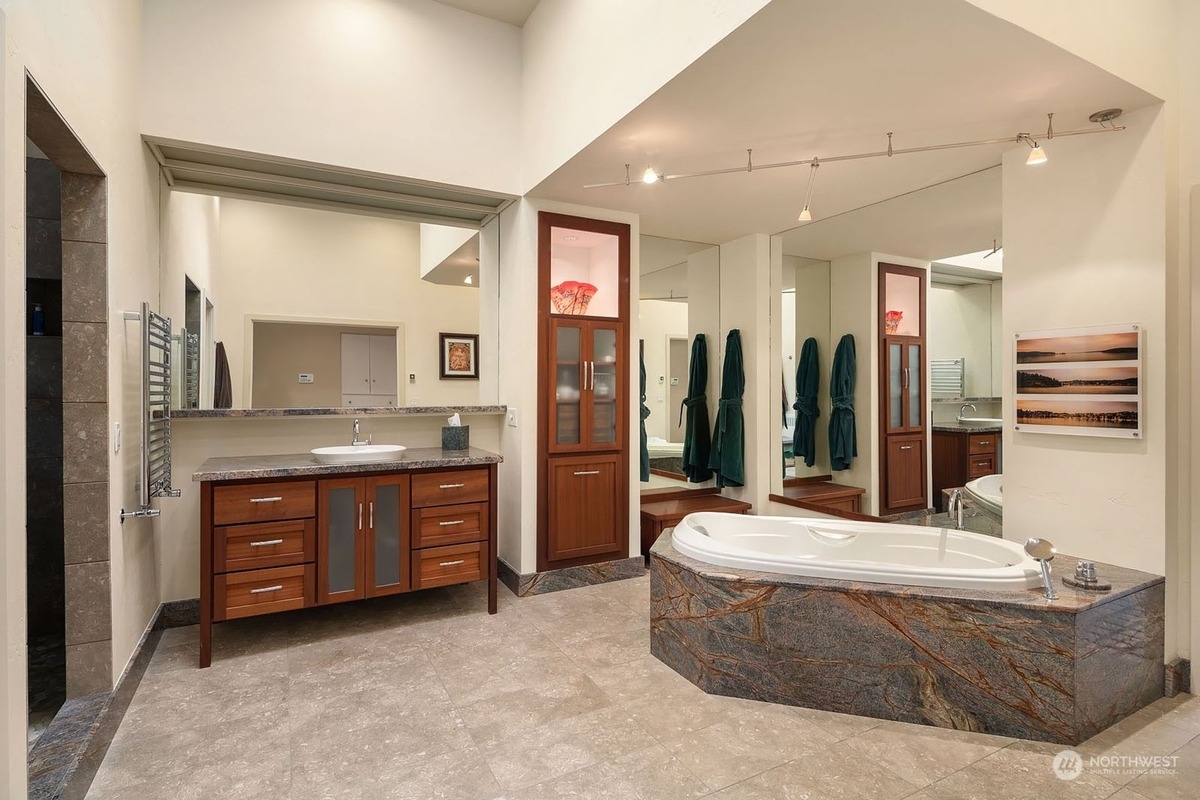 Spacious master bathroom boasts a large soaking tub, wood cabinetry, and a heated towel rack.