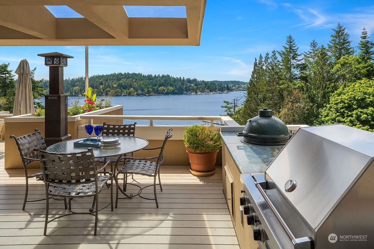 Outdoor patio with a table and chairs, built-in grill, and stunning lake view. 