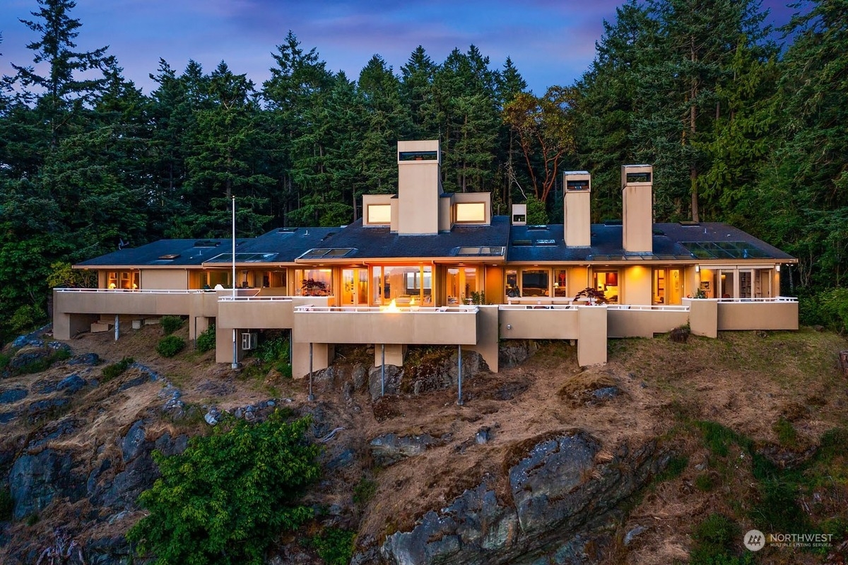 Expansive contemporary home perched atop a rocky hillside, offering panoramic views and a dramatic architectural design.