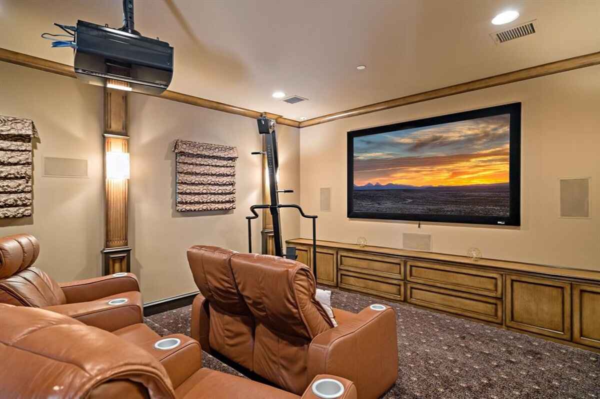 Alternate view of the theater room highlighting the large screen and comfortable setting.