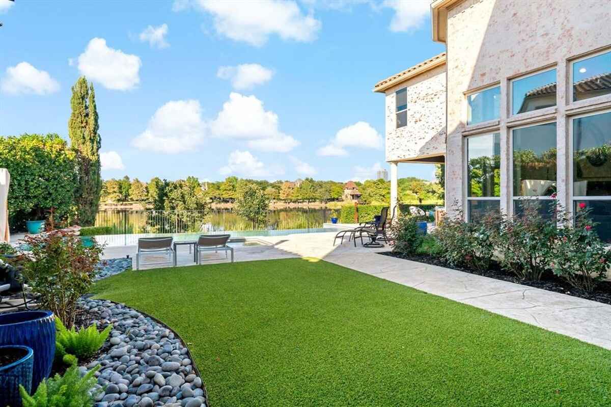 A landscaped yard with artificial grass and a view of the lake beyond.