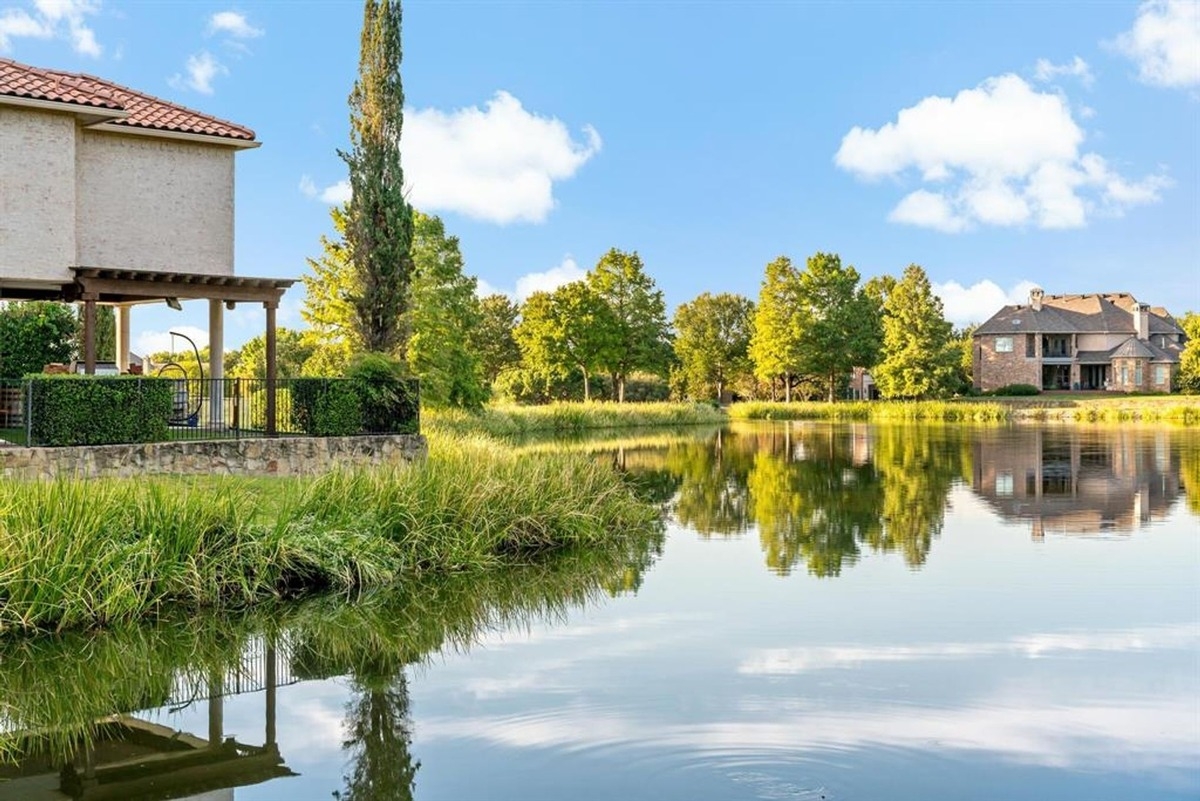 A serene view of the lake with reflections of trees and homes on the water.