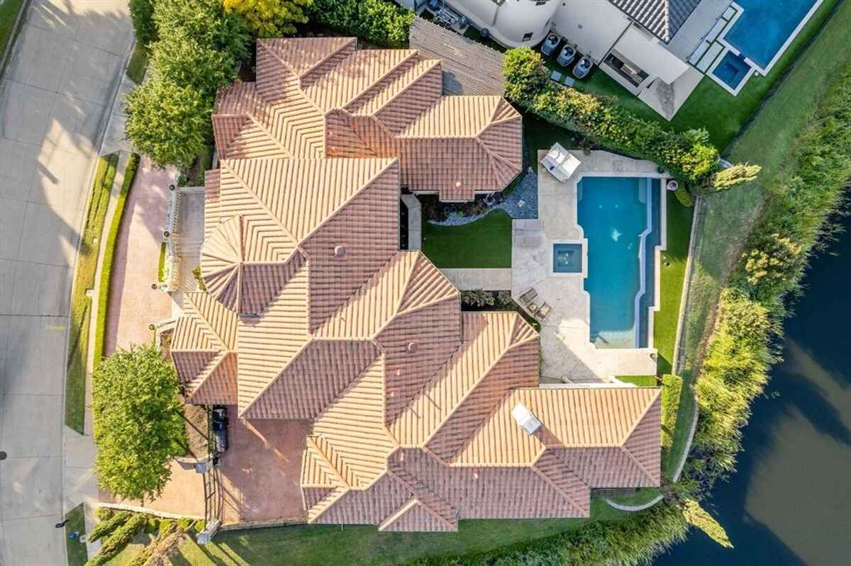 Overhead shot of a large home with tiled roof, pool, and landscaped yard.