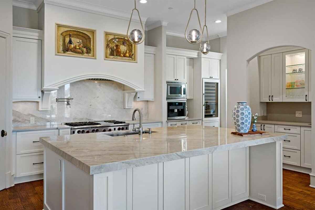 Modern kitchen with white cabinetry, marble countertops, and a central island.