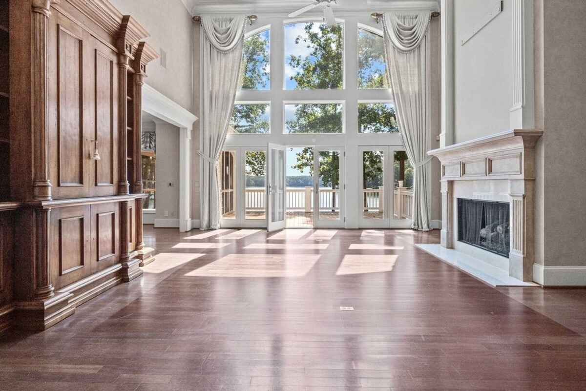 Large family room with expansive windows, a fireplace, and views of the outdoor deck and lake.