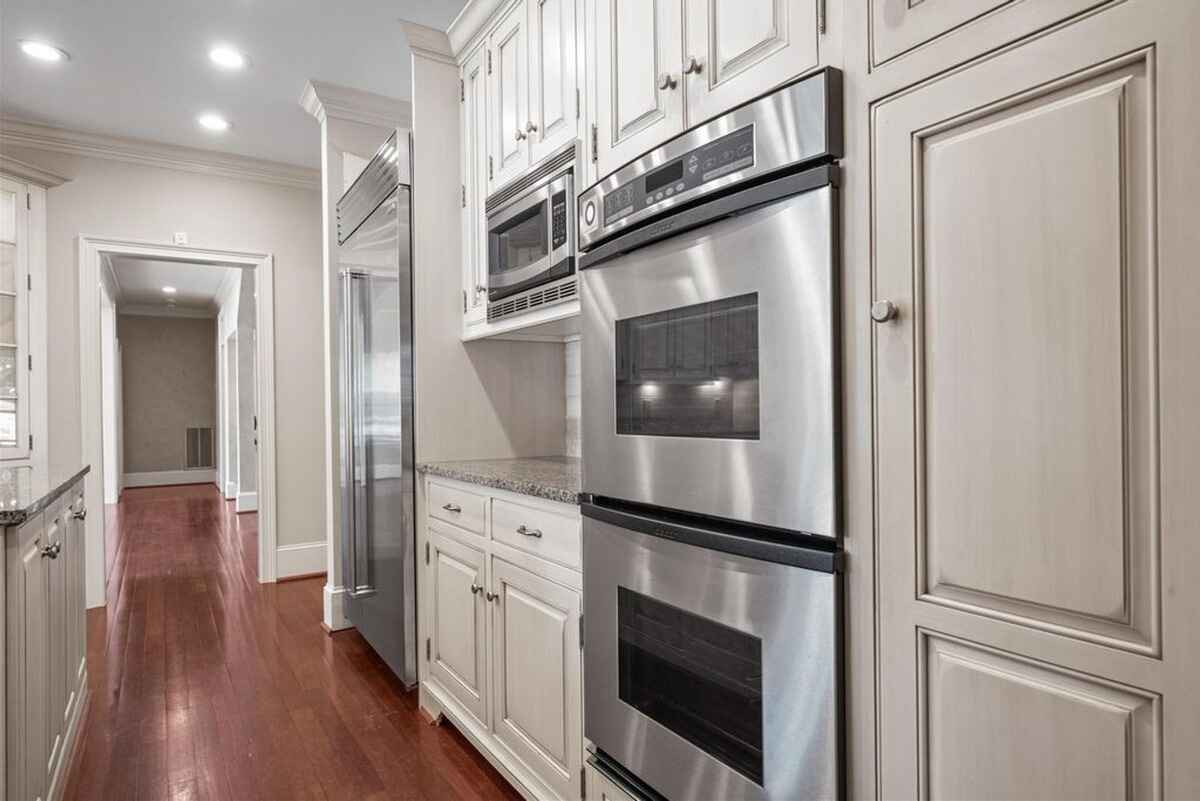 Spacious kitchen features white cabinetry, granite countertops, and a central island with built-in appliances.