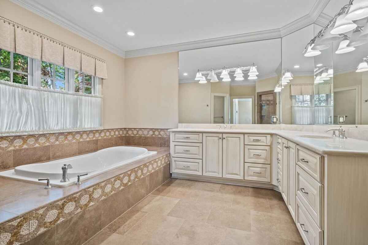 Elegant bathroom includes a double vanity, large soaking tub, and glass-enclosed shower.