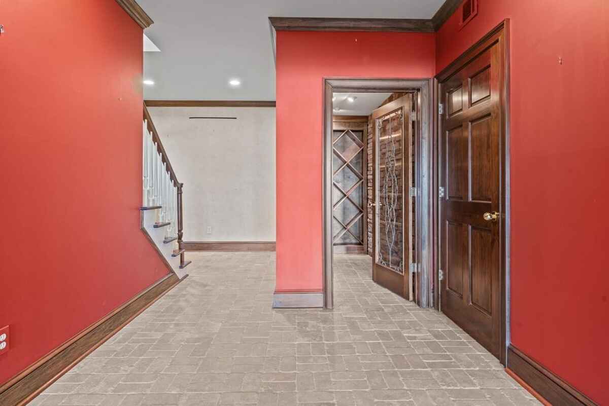 Hallway with red walls, wood trim, tiled floor, staircase, and doors leading to other rooms.