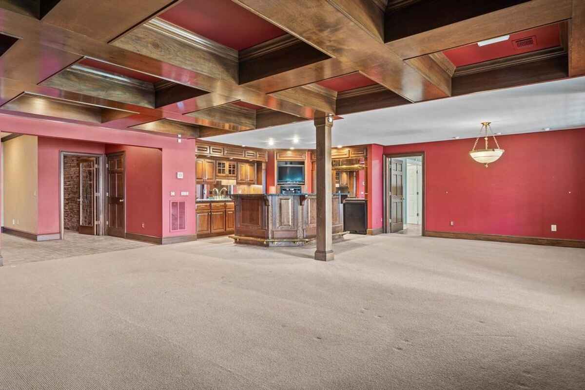 Entertainment area includes a custom-built bar, open seating space, and warm red walls.