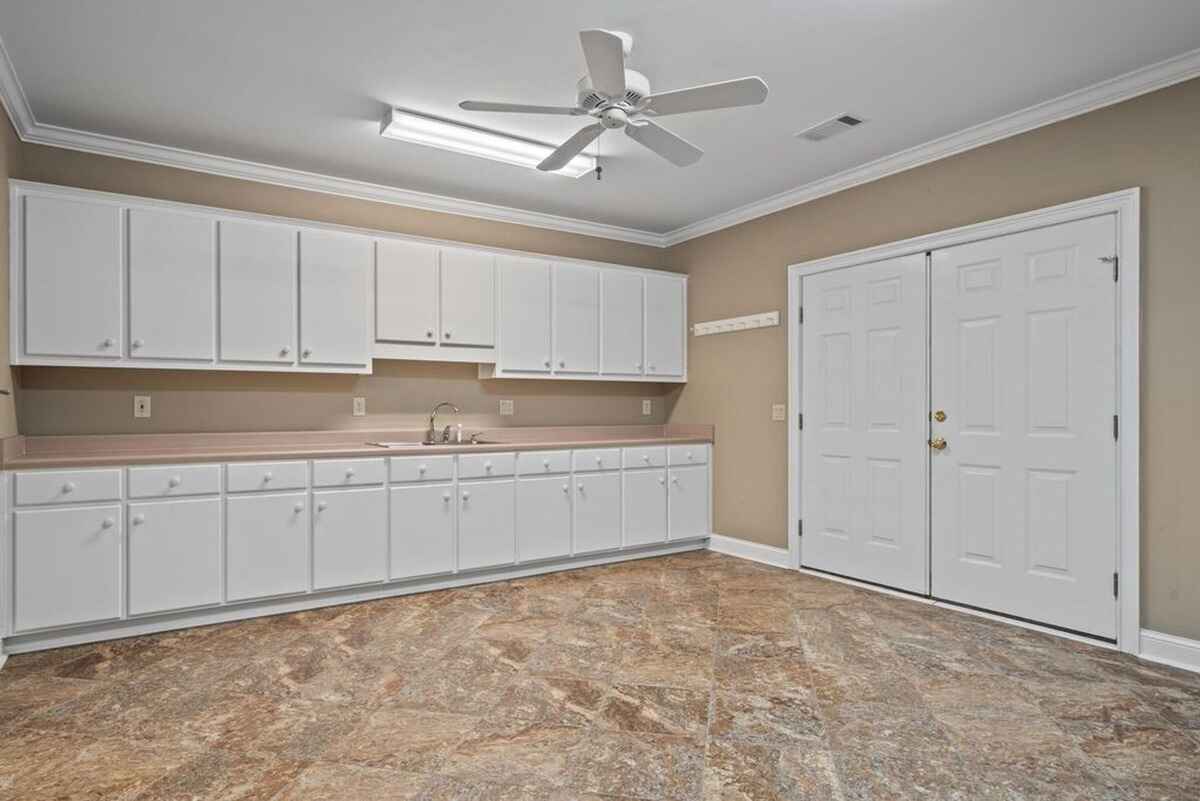 Large utility room showcases ample cabinetry, tiled flooring, and a ceiling fan.