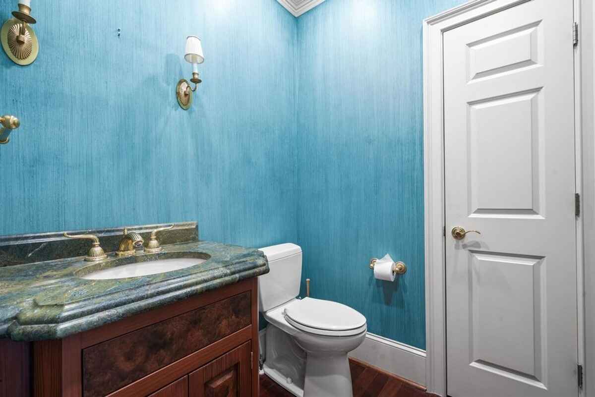 Powder room with blue walls, a green marble vanity, and gold fixtures.