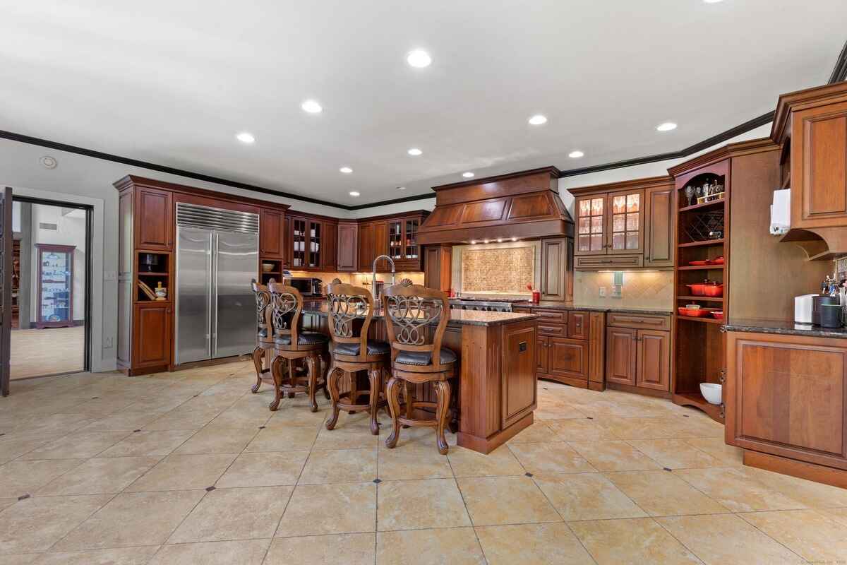 Large kitchen with dark wood cabinets, a kitchen island, and tile flooring.