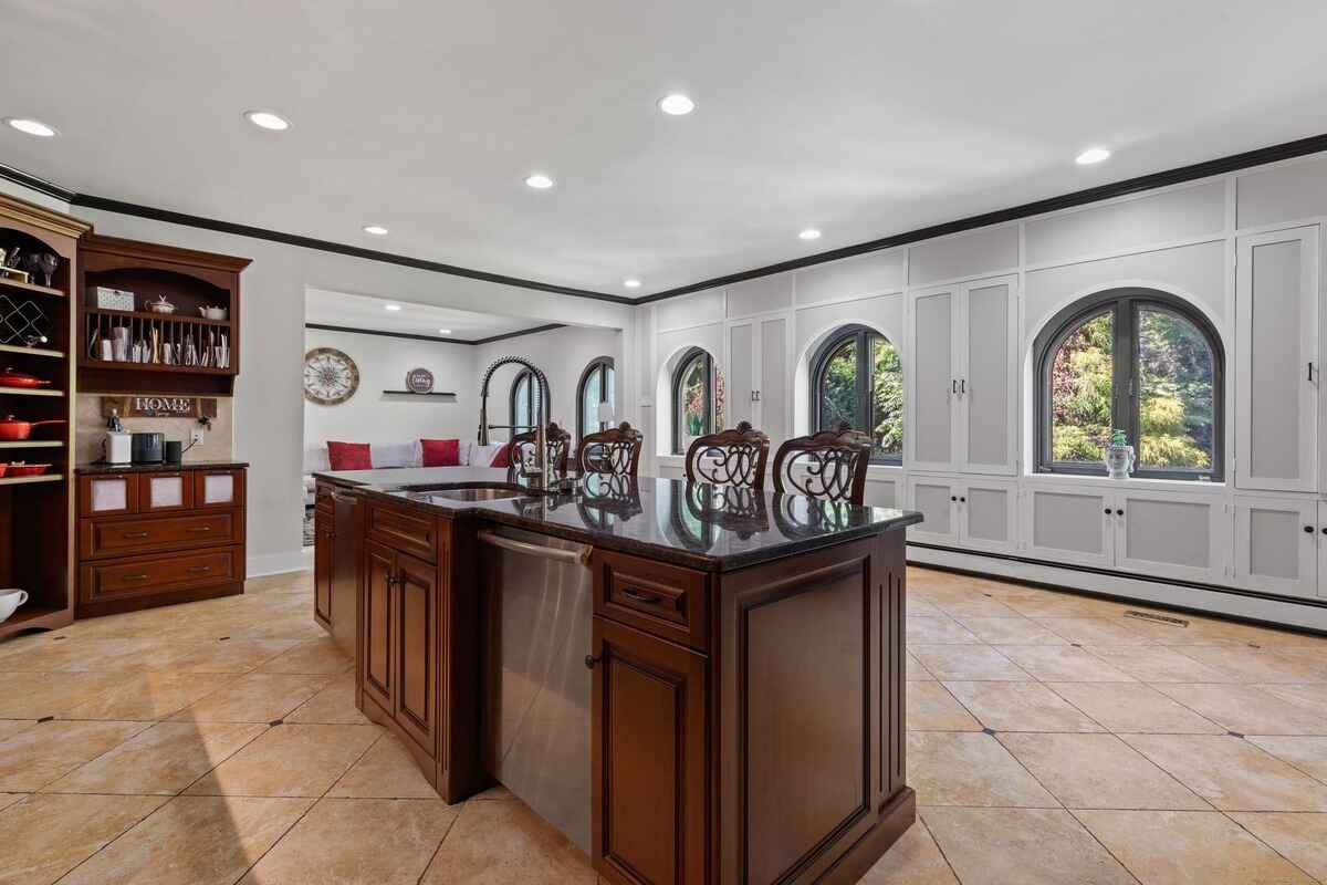 Kitchen with dark wood cabinetry, granite countertops, and arched windows.