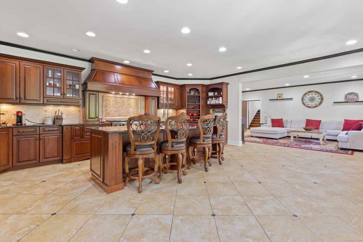 Kitchen with dark wood cabinets and island, opening to a living area with a sectional sofa.