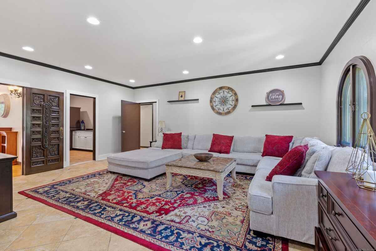 Living room with a large sectional sofa, area rug, and ornate doors leading to other rooms.