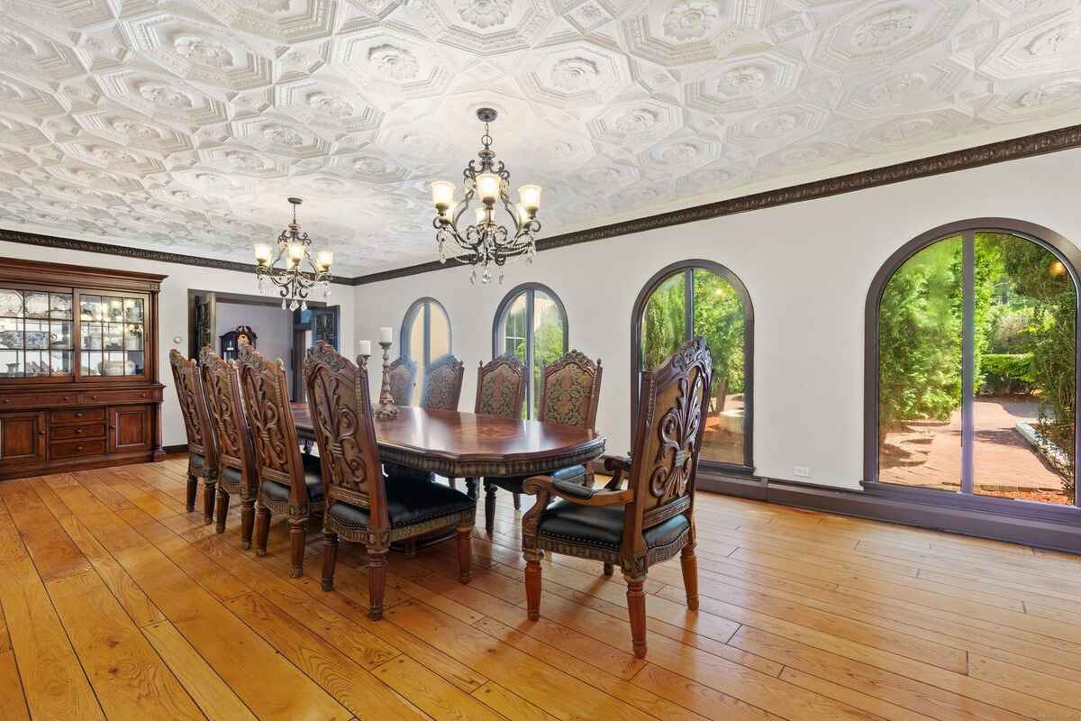 Formal dining room with hardwood floors, arched windows, and an ornate ceiling.