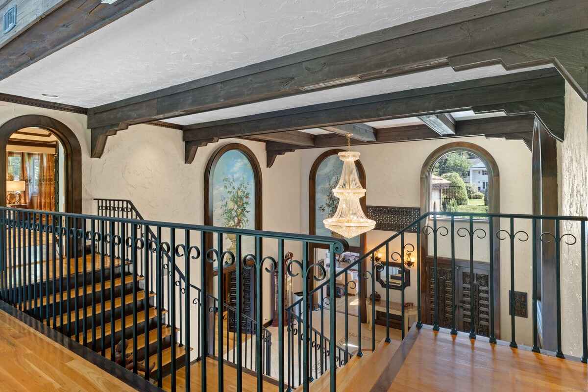 Upper-level landing overlooking a grand entryway with a chandelier and ornate doors.