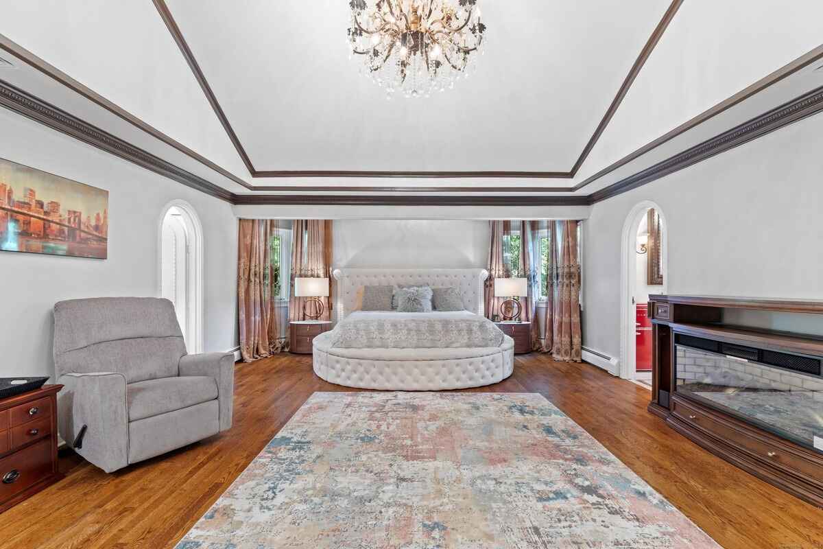 Master bedroom with hardwood floors, a large round bed, and a coffered ceiling.