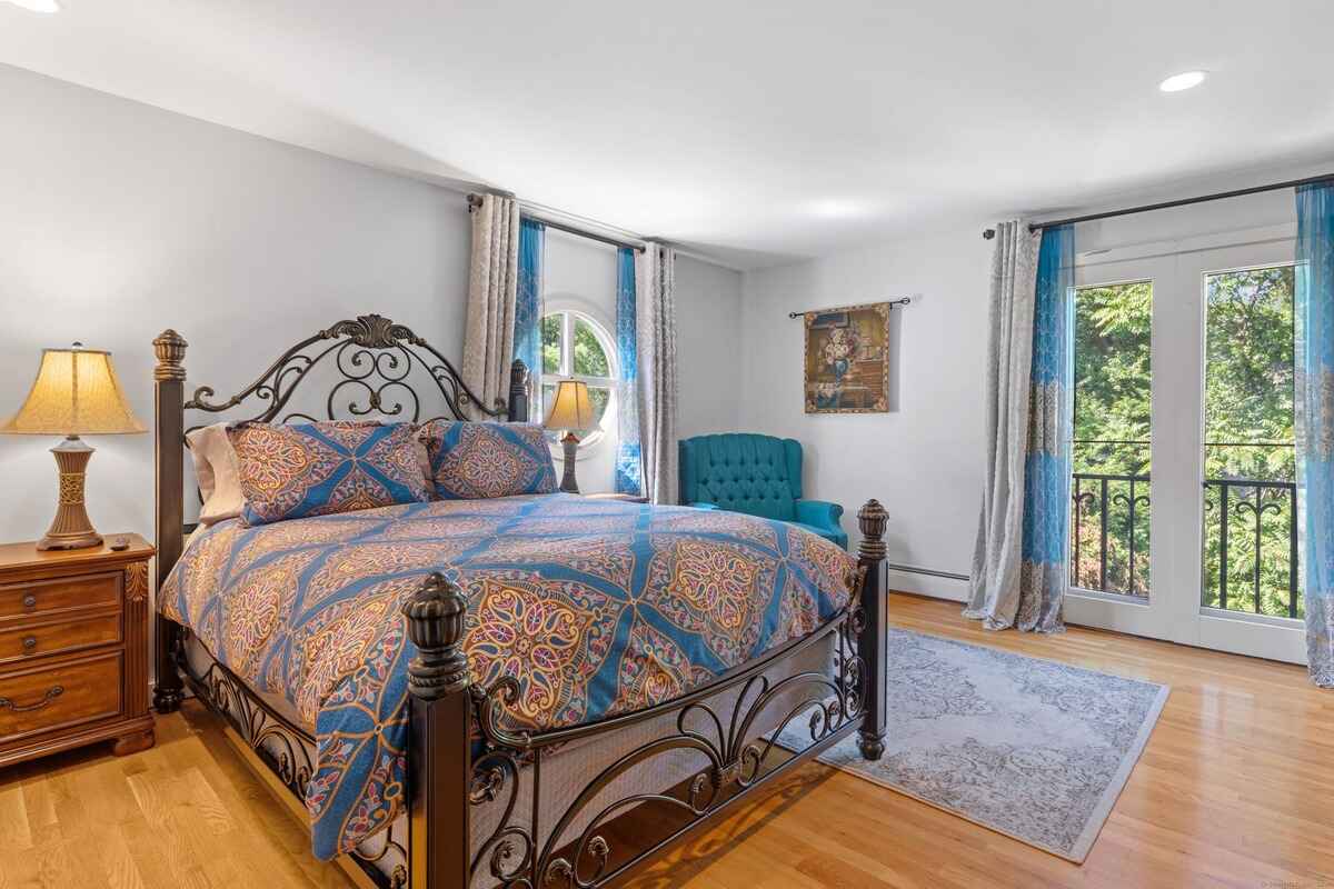 Bedroom with hardwood floors, a bed with an ornate metal frame, and French doors leading to a balcony.