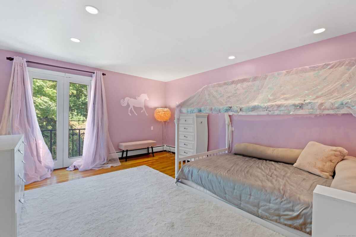 Child's bedroom with pink walls, a daybed with a canopy, and French doors leading to a balcony.